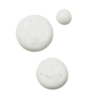 Three dollops of white serums with tiny blue specks, arranged on a plain white background.
