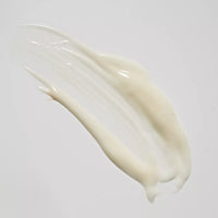 A thick, creamy white cosmetic smear on a plain light gray background.
