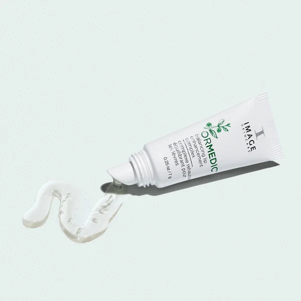 A white tube of IMAGE skincare lip treatment cream with green text, shown lying on its side with a dollop of white cream in front, against a pale mint green background.
