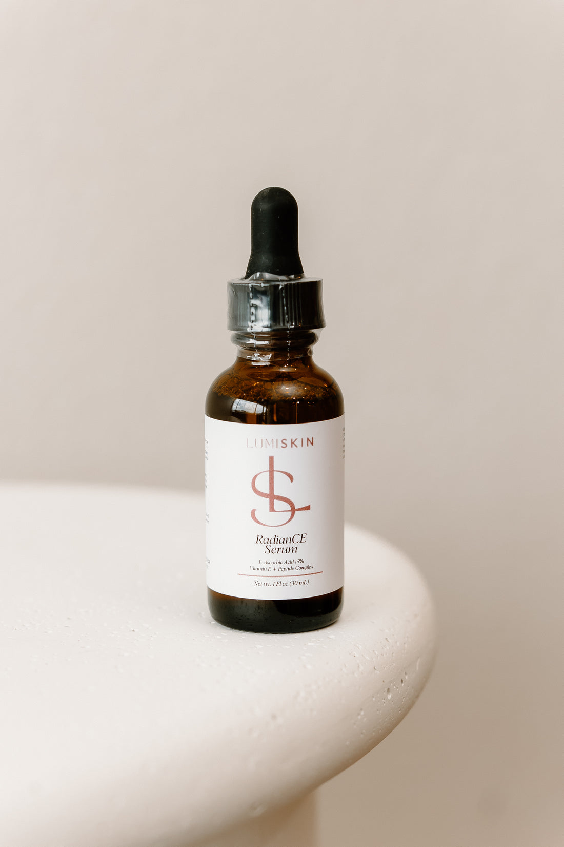 LUMISKIN RadianCE  serum in a brown dropper bottle on a white table in front of a white background